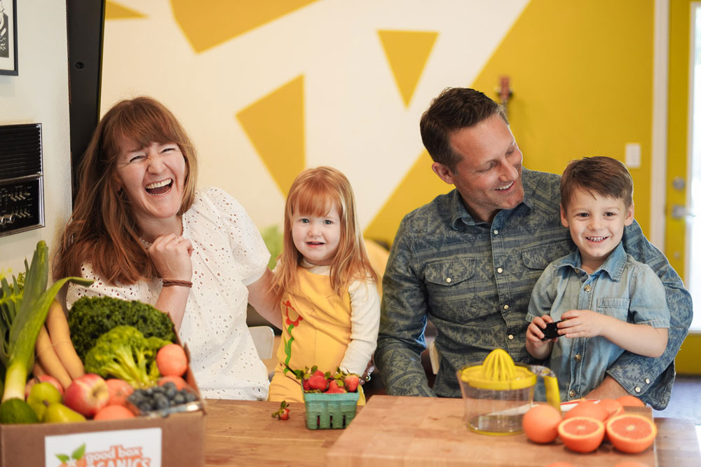 two parents and two young kids enjoying their produce box