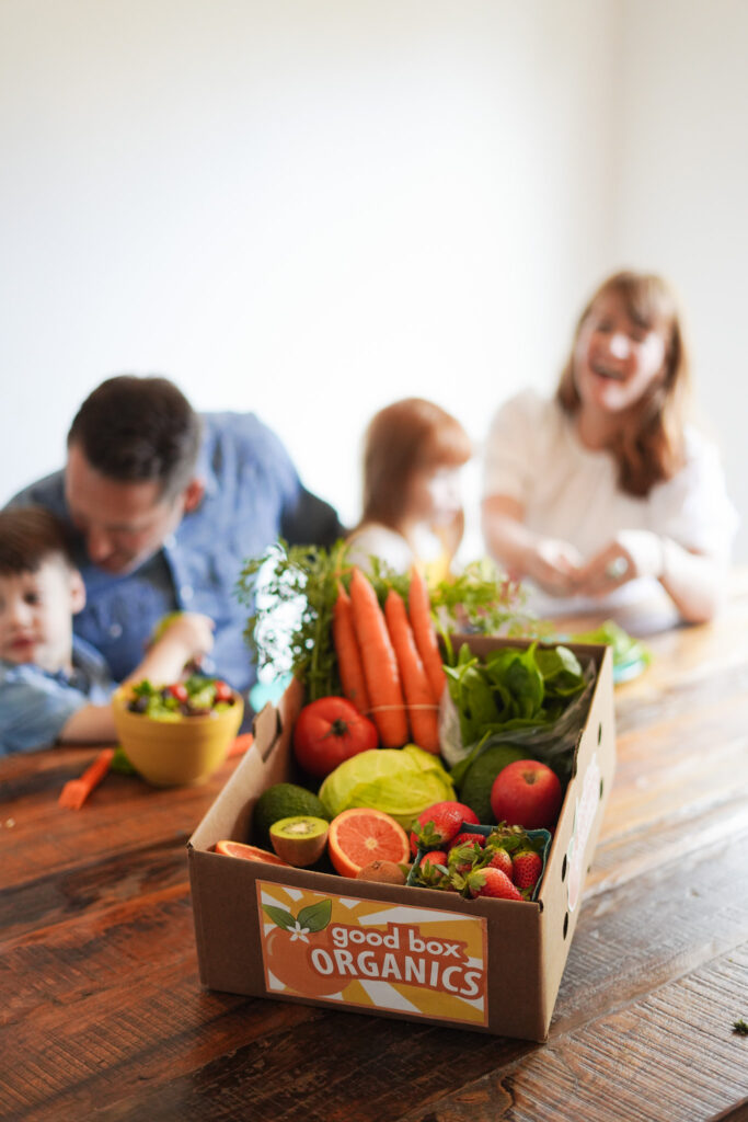 laughing family with box of produce on the table